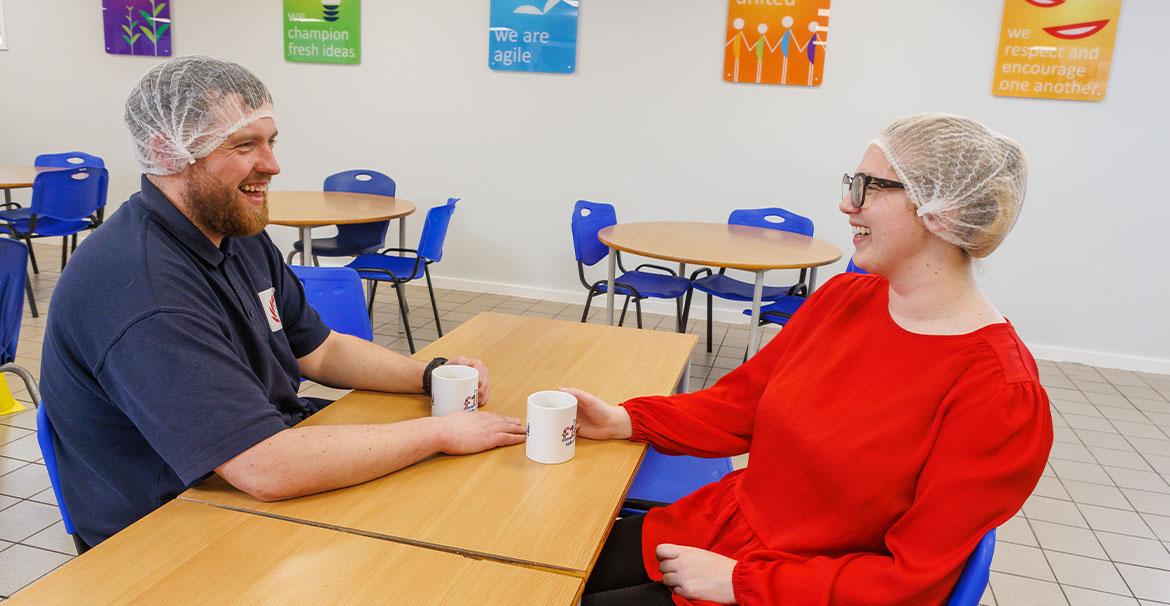 Two colleagues in canteen drinking coffee