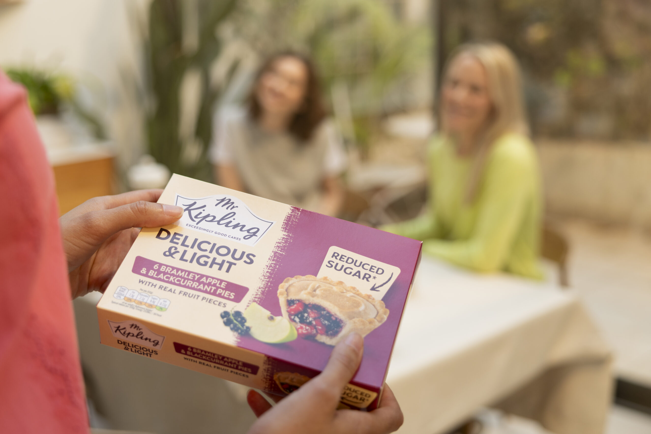 A packet of Mr Kipling Delicious & Light apple and blackcurrant pies being carried to a table